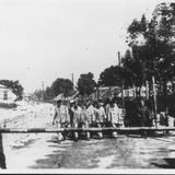 Grupa więźniów dochodząca do szlabanu. Zdjęcie archiwalne, czarno-białe.