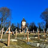 Cmentarz z kamiennymi obmurówkami i krzyżami, a wali drewniana kaplica.