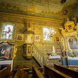 Wnętrze drewnianego kościoła - drewniana bogato zdobiona ambona, złocony ołtarz boczny z obrazem Matki Boskiej z Dzieciątkiem. Na ścianach i suficie polichromia, w oknach kolorowe witraże przedstawiające świętych.