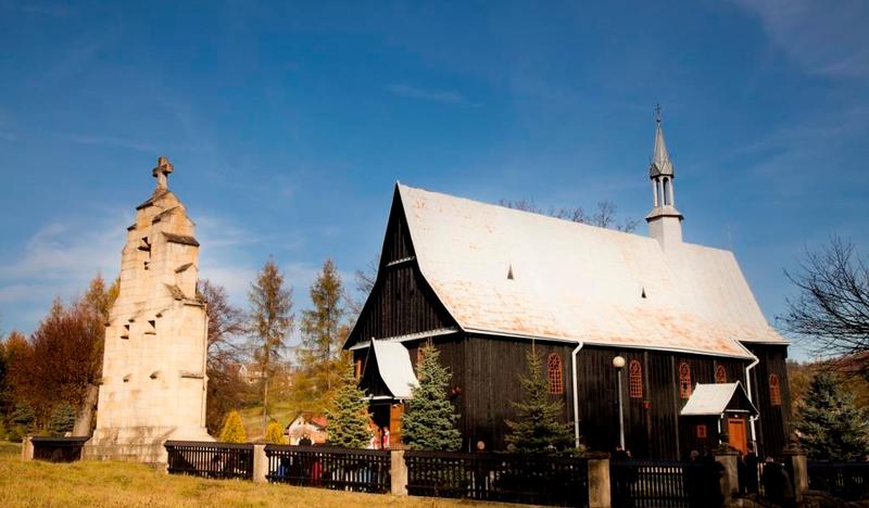 Drewniany kościół z kamienną dzwonnicą.
