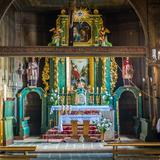 Wnętrze drewnianego kościoła - prezbiterium. Okazały ołtarz główny z kolorach ciemnej zieleni i złota.