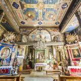 Bogato zdobione wnętrze drewnianego kościoła. W centralnym punkcie ołtarz główny z kolorze zielonym, po bokach ołtarze boczne - niebieski i czerwony. Bogate polichromie na suficie i ścianach.