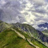 Kasprowy Wierch Tatry, zazieleniony szczyt nad którym rozciągają się chmury.