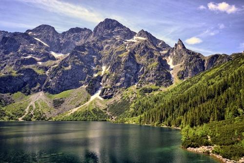 Panorama eines mit Eis und Schnee bedeckten Bergsees mit Gipfeln im Hintergrund