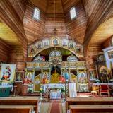 Drewniana cerkiew w środku, drewniane ściany, ołtarz i ołtarze boczne, chorągwie i ikony.