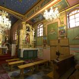Wnętrze drewnianego kościoła. Bogato zdobione dwa ołtarze, na ścianach i suficie polichromia.