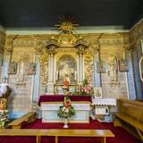 Wnętrze drewnianej cerkwi. W centralnym punkcie bogato złocony ołtarz boczny z figurą Chrystusa i obrazem. Po lewej stronie chrzcielnica.