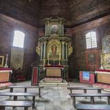 Wnętrze drewnianej kaplicy z ołtarzami i ławkami..