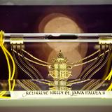 Szklana fiolka z relikwią krwi błogosławionego Jana Pawła II. Pod nią złota tarcza z insygniami papieskimi.