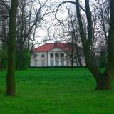 Pałac klasycystyczny za pięknym zielonym trawnikiem.
