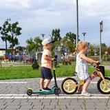 Dwoje dzieci, jedno na hulajnodze, drugie na rowerku w Miasteczku Ruchu Drogowego w Wieliczce.