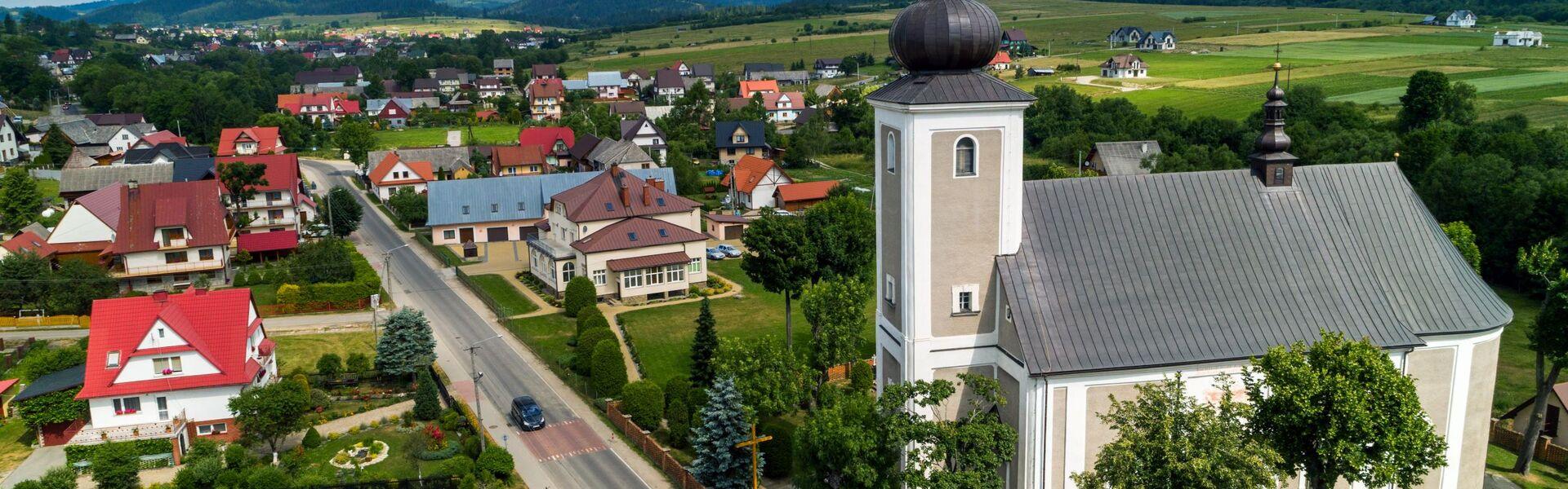 Panorama of Lipnica Wielka from a bird’s eye view, in the foreground the brick Church of St Luke the Evangelist, Babia Góra on the horizon.