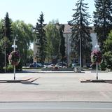 Na zdjęciu znajduje się Plac Tadeusza Kościuszki w Oświęcimiu, gdzie odbywają się różne uroczystości. W oddali widać Grób Nieznanego Żołnierza, wokół kwiaty, z tyłu budynek za drzewami.