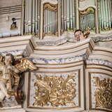 Zdobiony parapet chóru muzycznego, z tyłu muzyk i organy.