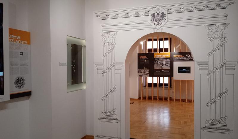 Przejście do wystawy dokumentującej dzieje Oświęcimia w czasach zaboru austriackiego w ratuszu oświęcimskim. Wokół otworu drzwiowego wymalowany łuk wsparty na dwóch kolumnach.