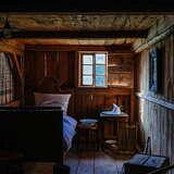 Wnętrze drewnianej izby z łóżkiem i toaletką.