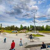 Osoby jeżdżące na hulajnodze, rowerze i deskorolce po terenie do skateboardu w Parku rekreacyjno-krajobrazowym Silver Park w Olkuszu.