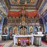 Wnętrze drewnianej cerkwi. Ołtarz główny, za nim ikonostas. Ściany i sufit pokrywa kolorowa polichromia, m.in. nad ikonostasem namalowany jest baldachim.