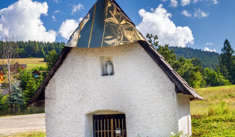 Pomalowana na biało murowana kapliczka z blaszanym dachem. Nad drzwiami z metalowych prętów figura Matki Boskiej.