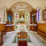 Kaplica w kościele, ołtarz z obrazem Chrystusa, drewniane ołtarze boczne, boazerie i ławki. Za klęcznikiem widać szklana płytę przykrywająca replikę grobu Jana Pawła II.