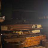 Pomieszczenie do produkcji oscypków w Bacówce Wojciecha Komperdy w Czorsztynie. W ciemnym pokoju znajdują się wytworzone oscypki, beczki i kilka narzędzi do wytwarzania tego specjału.
