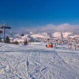 Narciarze na stacji Master Ski w Tyliczu w słoneczny zimowy dzień, w tle widok na krajobraz miejscowości