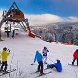 Grupa narciarzy na stacji Tylicz Ski, w tle widok na wyciąg krzesełkowy