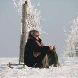 kobieta siedząca zimą na śniegu przy uprawach winorośli