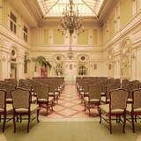 Elegancka sala konferencyjna w Grand Hotelu z kilkoma rzędami wyściełanych krzeseł, widziana od tyłu