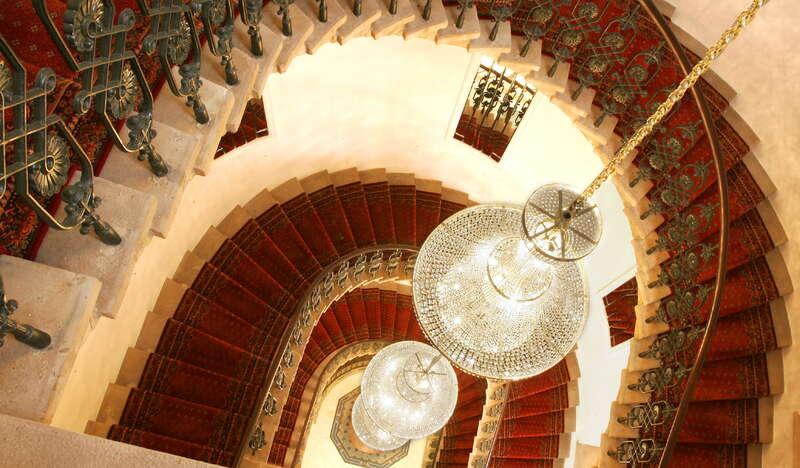 Długi, imponujący żyrandol wykonany z kryształu na klatce schodowej.