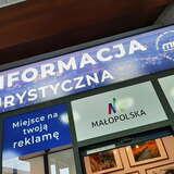 Niebieski szyld Punktu Informacji Turystycznej na dworcu MDA w Krakowie z napisem 