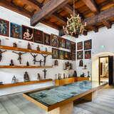 Sala w Muzeum im. Fishera z ekspozycją sakralnych figurek, obrazów ze świętymi oraz drewnianym stropem. Na środku stoi stół ze szklaną gablotą i eksponatami wewnątrz niej.