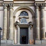 Żelazne drzwi w bramie prowadzącej do wnętrza Kościoła św. Anny w Krakowie. Obok drzwi po jednej jak i drugiej stronie znajdują się dwie wysokie, korynckie kolumny.
