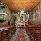 Dwa rzędy drewnianych ławek prowadzące do małego ołtarza w Kościele św. Jana Chrzciciela i MB Szkaplerznej w Krakowie. Ściany oraz sufit w świątyni są drewniane.