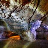 Widok wnętrza jaskini Nietoperzowefj w Jerzmanowicach z oświetlonymi skałami.