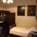 Pokój z zasłanym łóżkiem, szafa i dwa obrazy na ścianie.