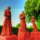 Gliniane figury trzech świętych w kolorze brązowo-rudym - dwie kobiety i jeden mężczyzna.